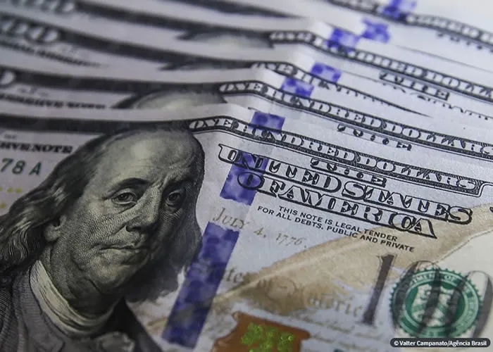 Num dia de ajustes no mercado, o dólar teve forte queda, mas fechou a semana em alta. A bolsa de valores ficou praticamente estável e apresentou leve queda na semana.

O dólar comercial encerrou esta sexta-feira (10) vendido a R$ 5,222, com queda de R$ 0,057 (-1,08%). A cotação iniciou o dia em alta, aproximando-se dos R$ 5,30 nos primeiros minutos de negociação, mas desacelerou e passou a cair ainda antes da abertura do mercado norte-americano. Na mínima do dia, por volta das 16h15, chegou a R$ 5,21.

Apesar da queda de hoje, a moeda norte-americana fechou a semana com alta de 1,49%. Em 2023, a divisa acumula recuo de 1,1%.

O mercado de ações teve um dia mais turbulento. O índice Ibovespa, da B3, fechou aos 108.078 pontos, com alta de apenas 0,07%. O indicador oscilou bastante ao longo do dia, com as ações da Petrobras, as mais negociadas, compensando a queda de ações de bancos.

Após dias de instabilidade em meio a trocas de declarações tensas entre o presidente Luiz Inácio Lula da Silva e o presidente do Banco Central, Roberto Campos Neto, o mercado teve um dia de realização de lucros. Investidores, principalmente exportadores, aproveitaram o dólar alto para venderem a moeda norte-americana. Com a viagem de Lula aos Estados Unidos e sem fatos econômicos novos, o mercado teve um dia mais tranquilo.

Outro fator que contribuiu para o otimismo dos investidores foi a divulgação do crescimento de 8,3% no setor de serviços em 2022, segundo o Instituto Brasileiro de Geografia e Estatística (IBGE). Reflexo da recuperação da atividade após a pior fase da pandemia de covid-19, a expansão dos serviços ajuda a melhorar as perspectivas para o Produto Interno Bruto (PIB) em 2023., Como investir em dólar, Empiricus Como Investir e Câmbio OnLine, em, Brasil